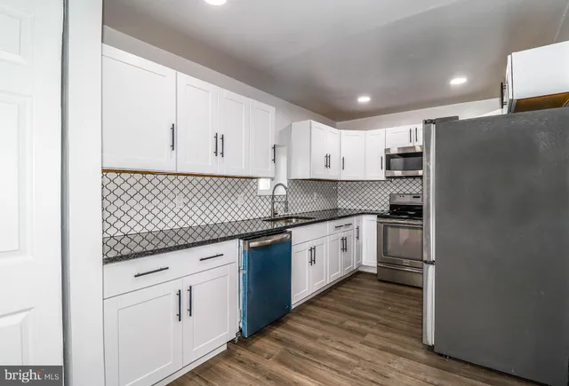 a kitchen with granite countertop white cabinets and stainless steel appliances
