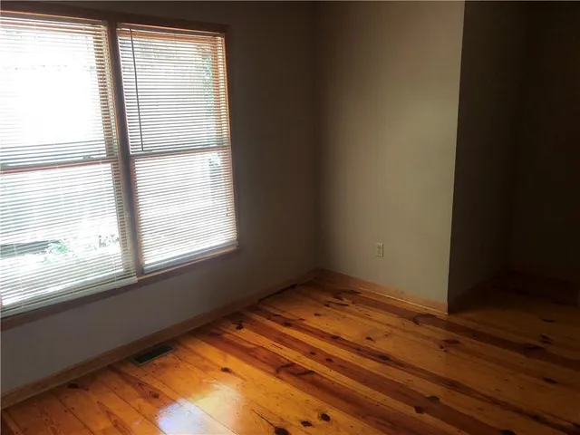 a view of an empty room with window and wooden floor