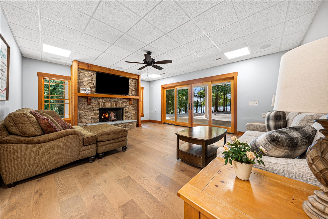 285 Bertha Allen Road Westminster, SC 29693 - Photo 21 of 50 A striking stone fireplace anchors this living space, offering warmth and direct views of the lake through expansive glass doors.