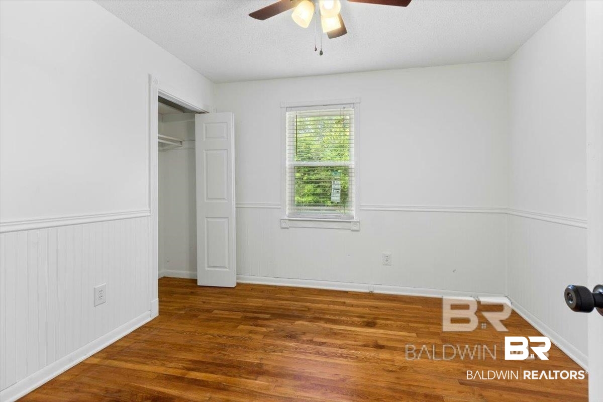 29397 Loper Road Loxley, AL 36551 - Photo 15 of 22 Unfurnished bedroom with a textured ceiling, a closet, wood finished floors, wainscoting, and ceiling fan