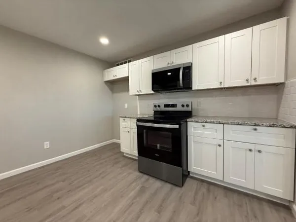 a kitchen with stainless steel appliances granite countertop a stove a sink and a microwave