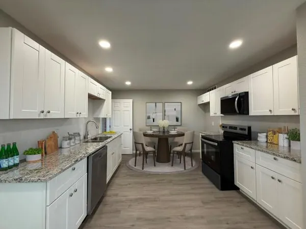a large kitchen with stainless steel appliances granite countertop a lot of counter space and wooden floors