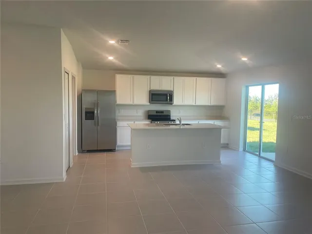 a large kitchen with stainless steel appliances granite countertop a stove a sink and a refrigerator