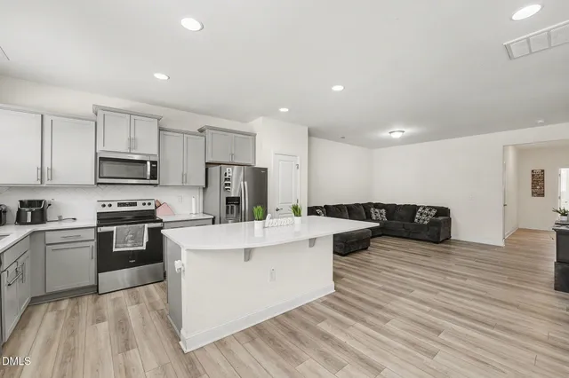 a kitchen with stainless steel appliances granite countertop a refrigerator a stove and a refrigerator with wooden floor