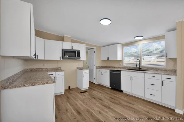 a kitchen with granite countertop white cabinets and stainless steel appliances