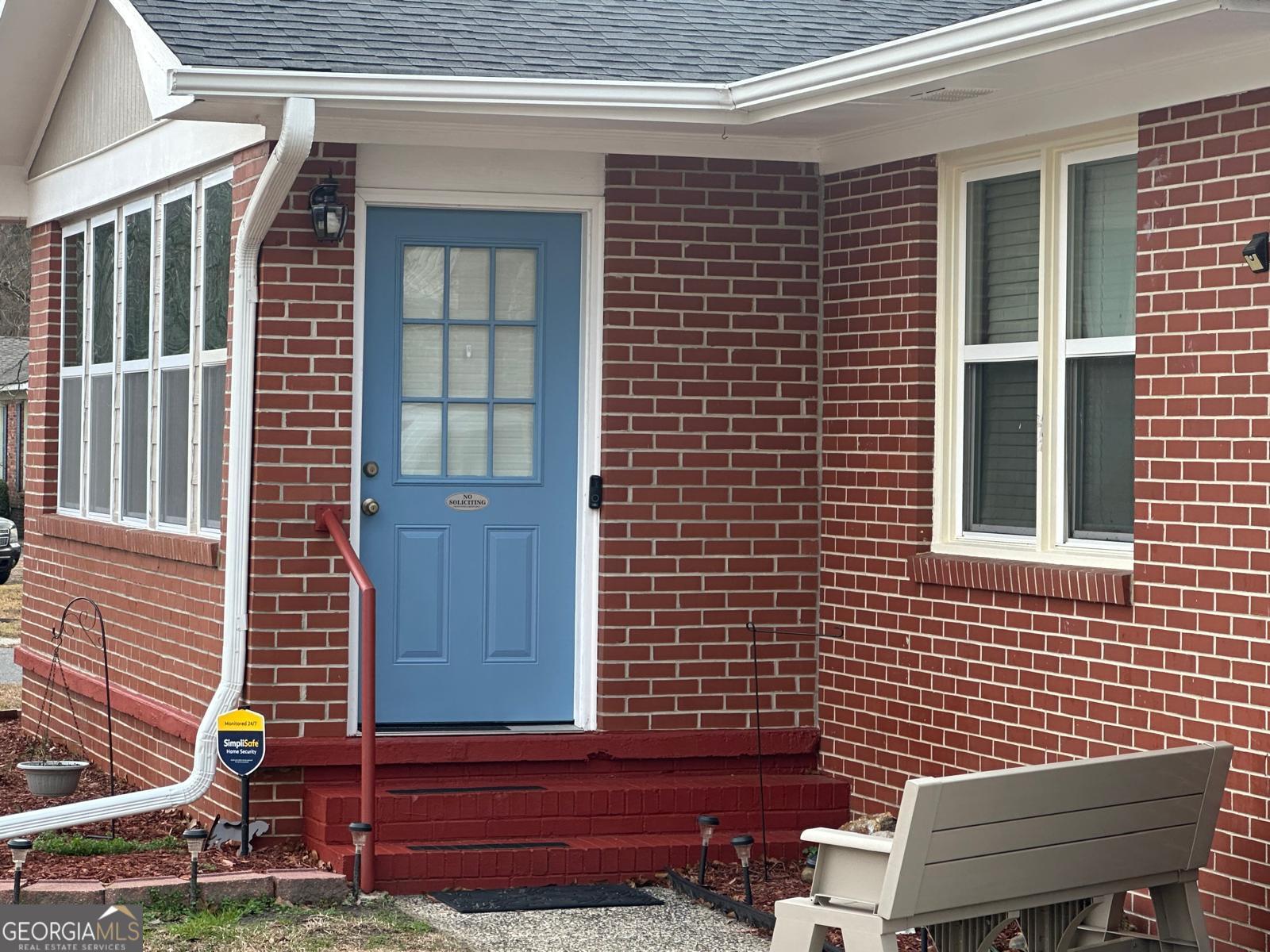a view of a brick house with a chairs in a backyard
