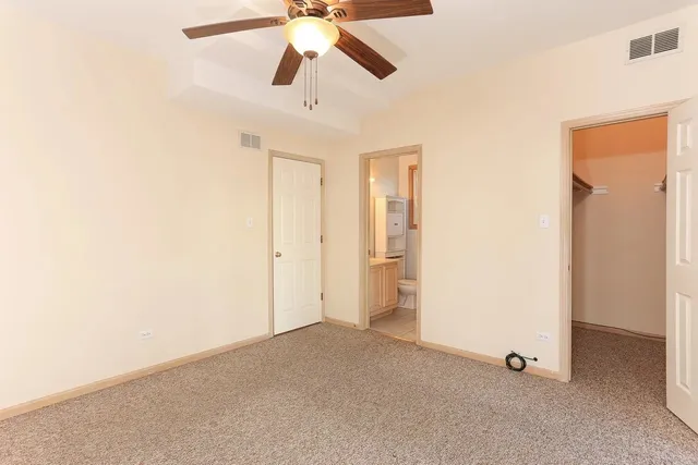 an empty room with chandelier fan and windows