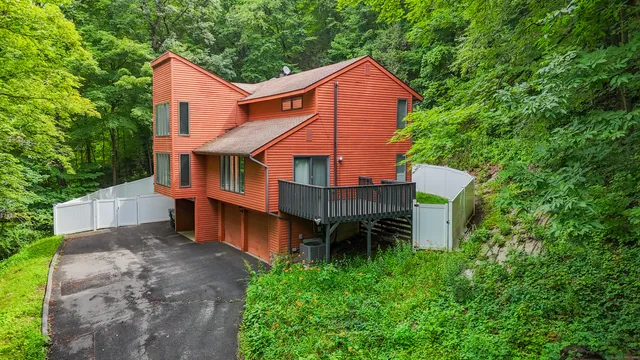 a view of a house with a yard plants and large tree