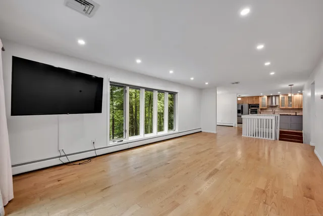 a view of an empty room with wooden floor and windows