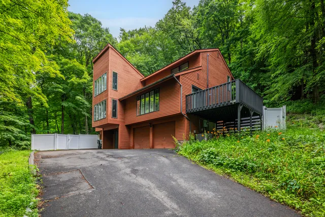 a view of a house with a yard plants and large tree