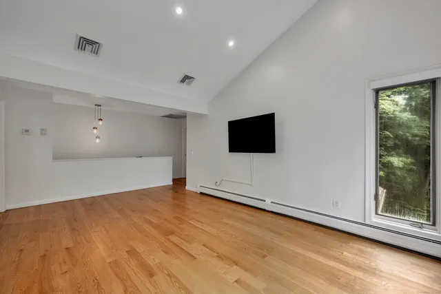 a view of an empty room with wooden floor and a window