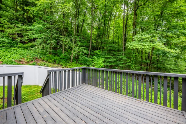 a balcony with wooden floor and trees in the back