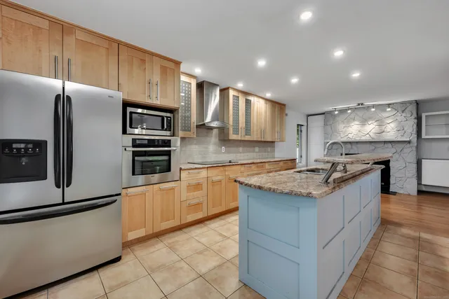 a kitchen with stainless steel appliances granite countertop a refrigerator a stove and a sink