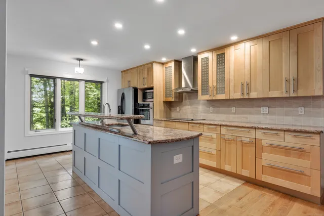 a kitchen with kitchen island granite countertop a stove sink and cabinets