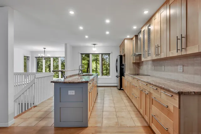 a kitchen with granite countertop a stove a sink and a refrigerator