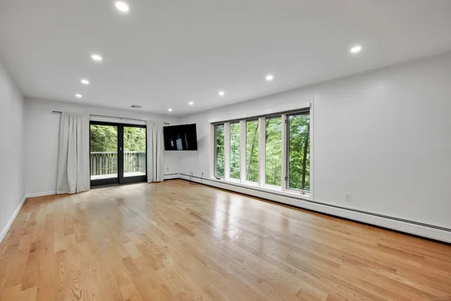 a view of an empty room with wooden floor and a window