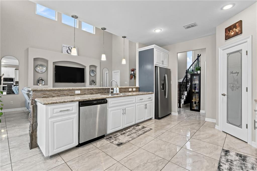 1904 Ridgeway Circle Edinburg, TX 78542 - Photo 4 of 32 Expansive kitchen featuring white cabinetry, stainless steel appliances, granite countertops, and tile flooring