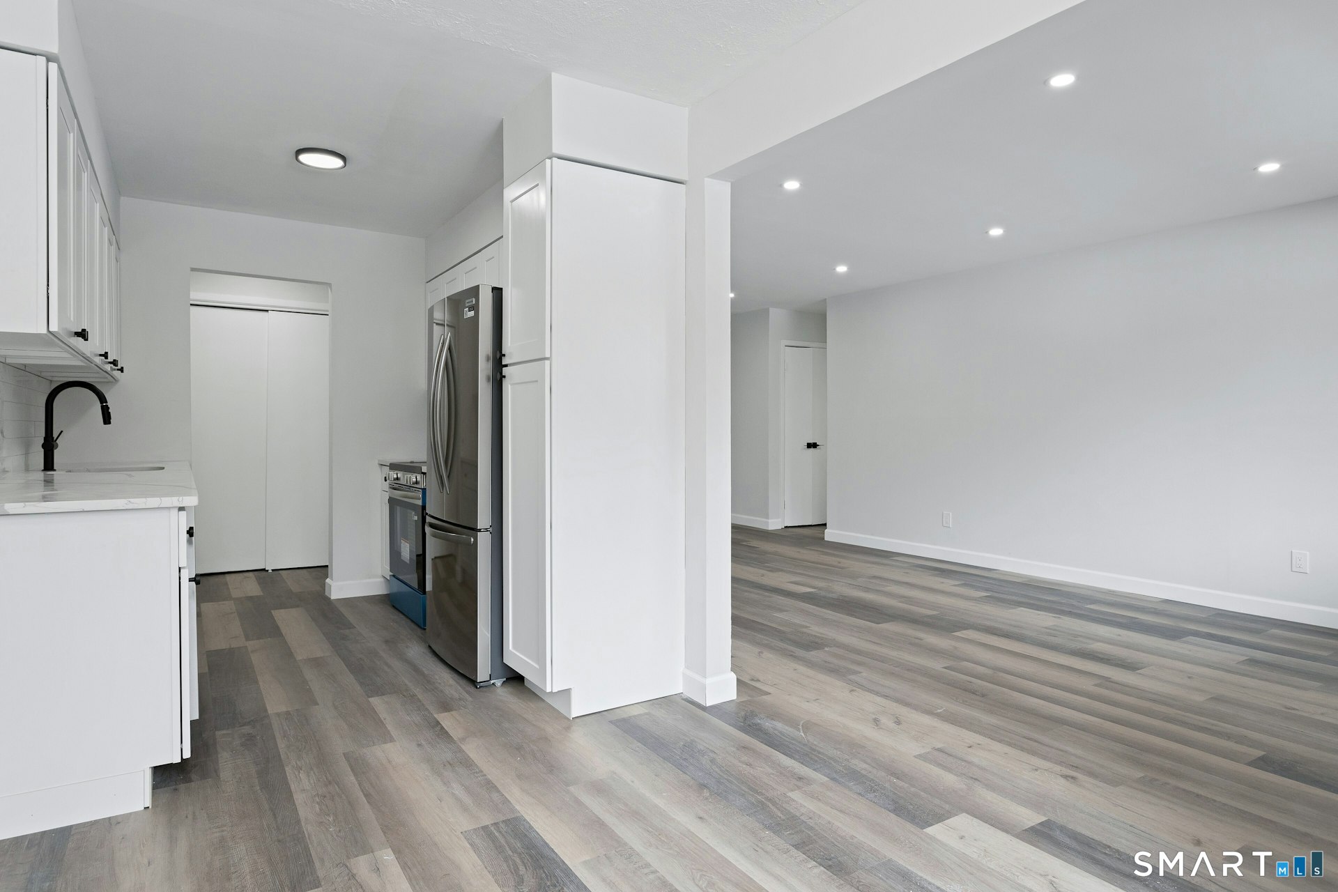 154 Cold Spring Road, Unit 18 Stamford, CT 06905 - Photo 14 of 28 a view of a refrigerator in kitchen and an empty room with wooden floor