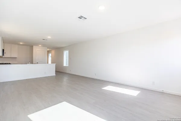 a view of an empty room with kitchen view and a window