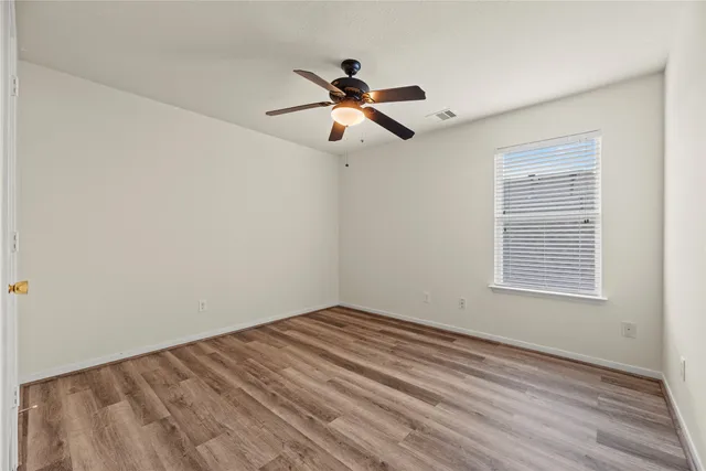 an empty room with windows and fan