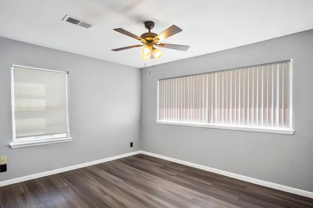 a view of an empty room with window and wooden floor