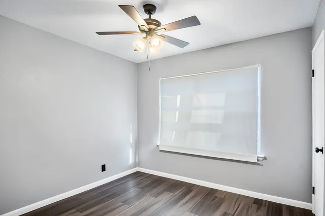 an empty room with a window and a fan