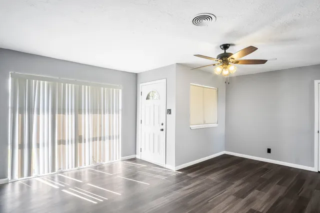 an empty room with wooden floor and windows