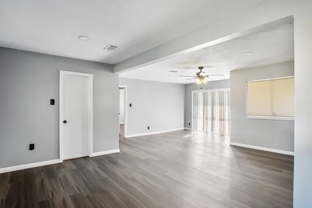 a view of an empty room with wooden floor and a window