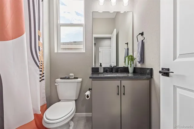 a bathroom with a granite countertop toilet a sink a mirror and a window