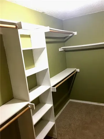 a view of walk in closet with clothes and shoes