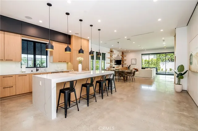 a kitchen with stainless steel appliances granite countertop a stove top oven a sink a dining table and chairs with wooden floor