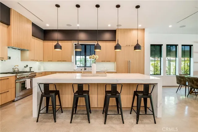 a kitchen with stainless steel appliances granite countertop a table chairs sink and cabinets