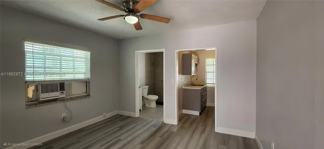 a view of empty room with wooden floor and fan