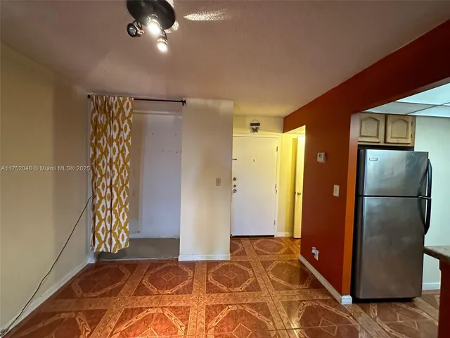 a view of an empty room with wooden floor and a ceiling fan