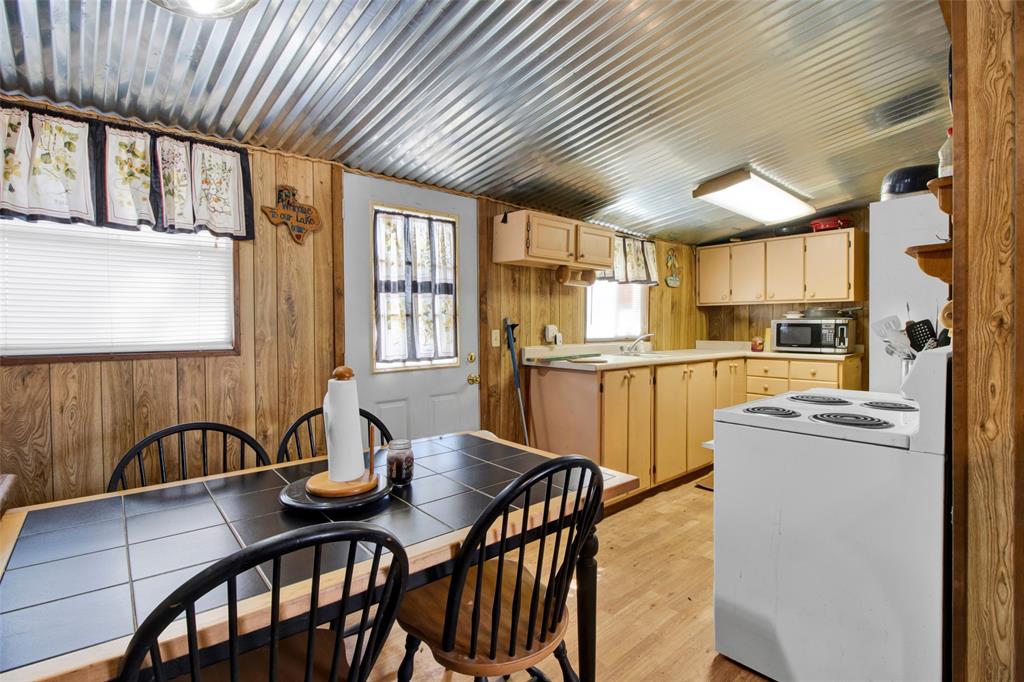 4185 Rock Creek Road Whitesboro, TX 76273 - Photo 16 of 18 Kitchen featuring white appliances, light wood-style floors, light countertops, vaulted ceiling, and wooden walls