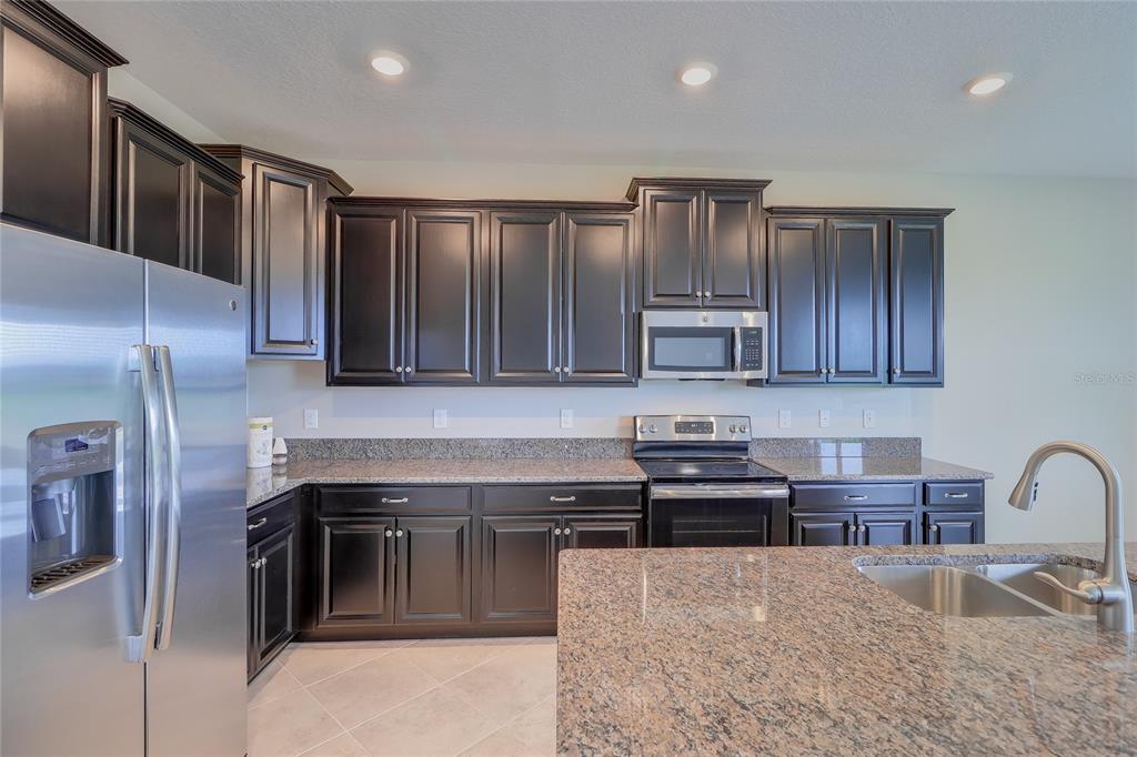 1172 Montgomery Bell Road Wesley Chapel, FL 33543 - Photo 16 of 47 a kitchen with granite countertop stainless steel appliances and wooden cabinets
