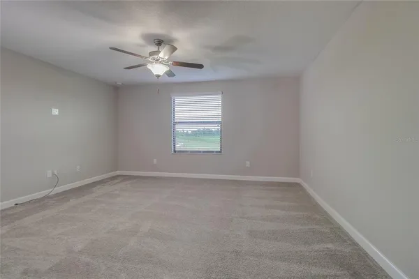 an empty room with a window and a fan
