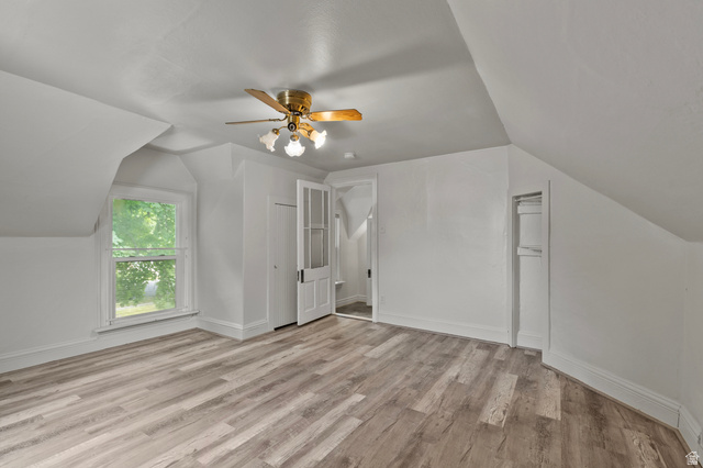 148 South 300 East Logan, UT 84321 - Photo 18 of 29 Attic space featuring wood-finish flooring, a window with exterior tree scenery, a ceiling fan with integrated lighting, and a white paneled door with glass inserts