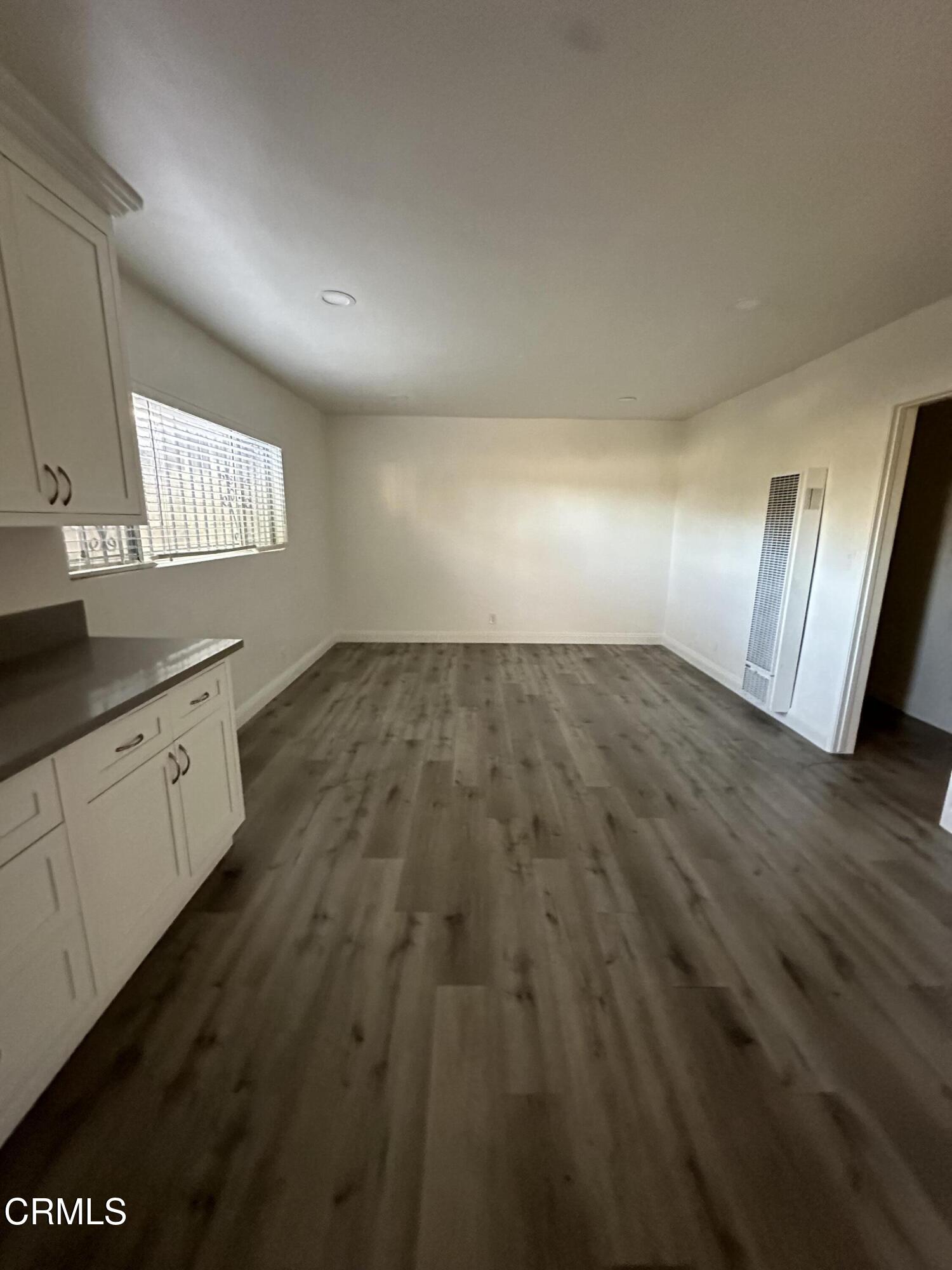 a view of empty room with wooden floor