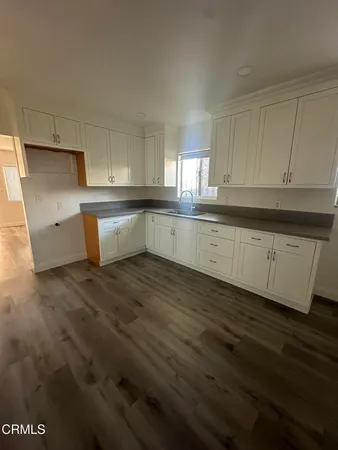 a large white kitchen with wooden floor