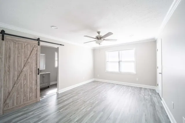 an empty room with wooden floor and a ceiling fan