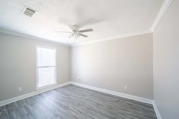 an empty room with wooden floor ceiling fan and windows