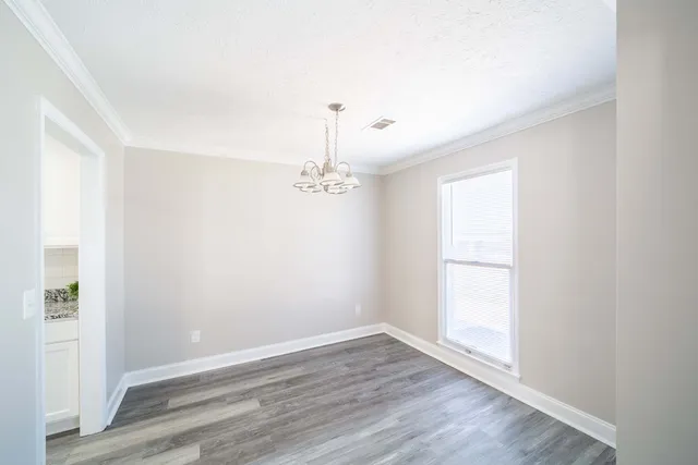 a view of a hallway with wooden floor and a chandelier