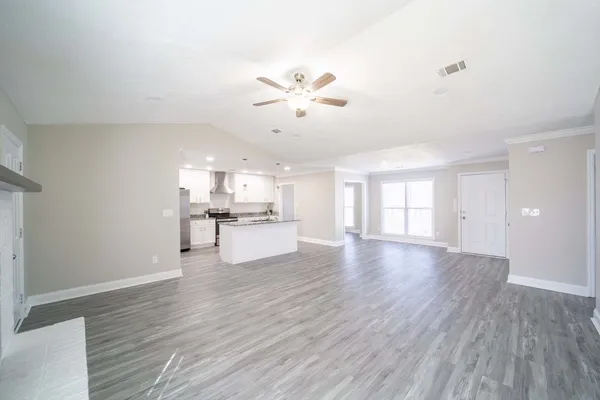 a view of a kitchen and an empty room with a fireplace