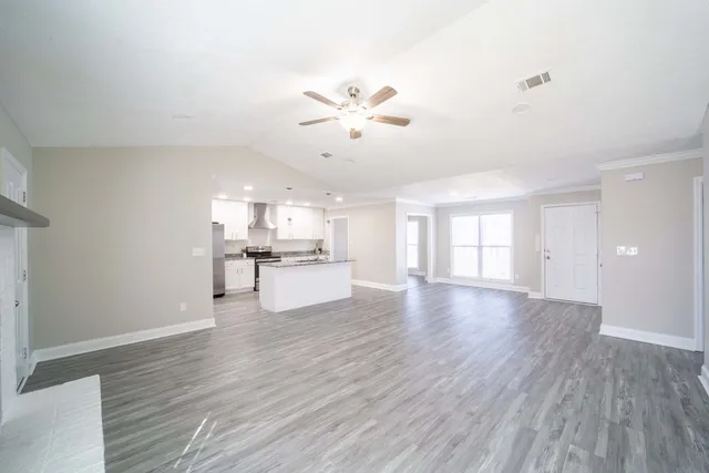 a view of a kitchen and an empty room with a fireplace