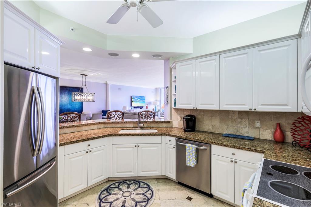 410 Flagship Drive, Unit 903 Naples, FL 34108 - Photo 11 of 29 a kitchen with granite countertop a sink stainless steel appliances and white cabinets