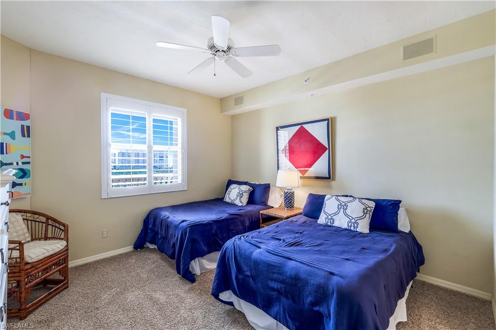 410 Flagship Drive, Unit 903 Naples, FL 34108 - Photo 19 of 29 a bedroom with two beds and a chandelier