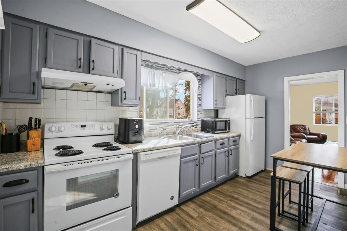 8 University Court Normal, IL 61761 - Photo 6 of 19 a kitchen with stainless steel appliances granite countertop a stove a sink dishwasher a refrigerator white cabinets and wooden floor