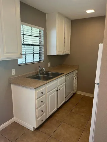 a kitchen with granite countertop white cabinets and sink