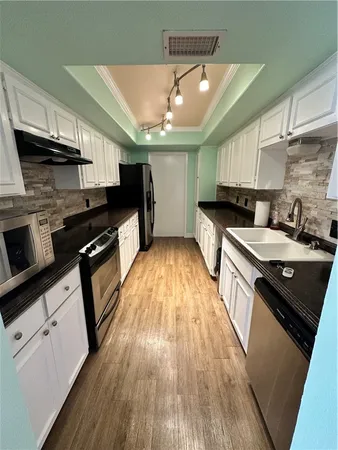 a kitchen with stainless steel appliances wooden floors wooden cabinets a stove a sink and a microwave